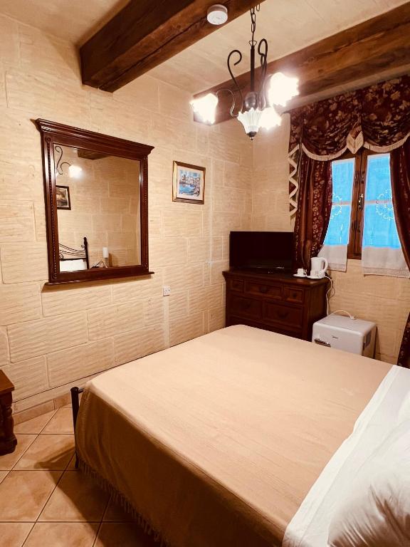 a bedroom with a large bed and a mirror at Narcisa Farmhouse B&B in Nadur