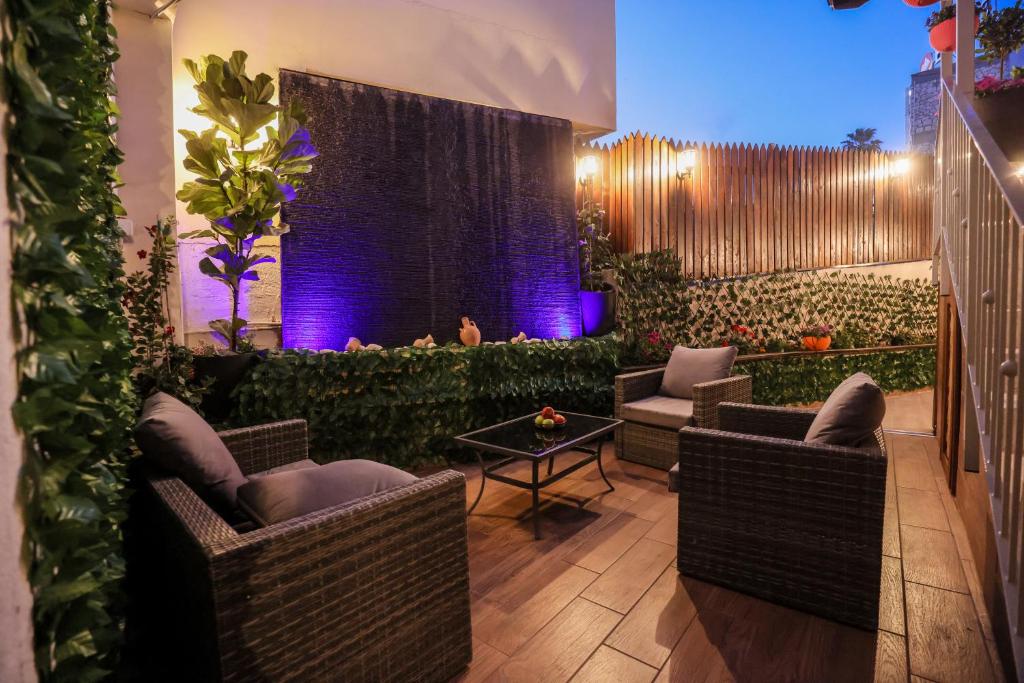 einen Garten mit Stühlen, einem Tisch und lila Lichtern in der Unterkunft Mary's Well Apartments in Nazareth
