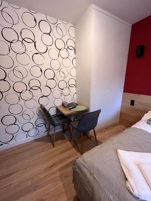 Compact workspace with two chairs, small wooden table and circular-patterned accent wall beside wardrobe.