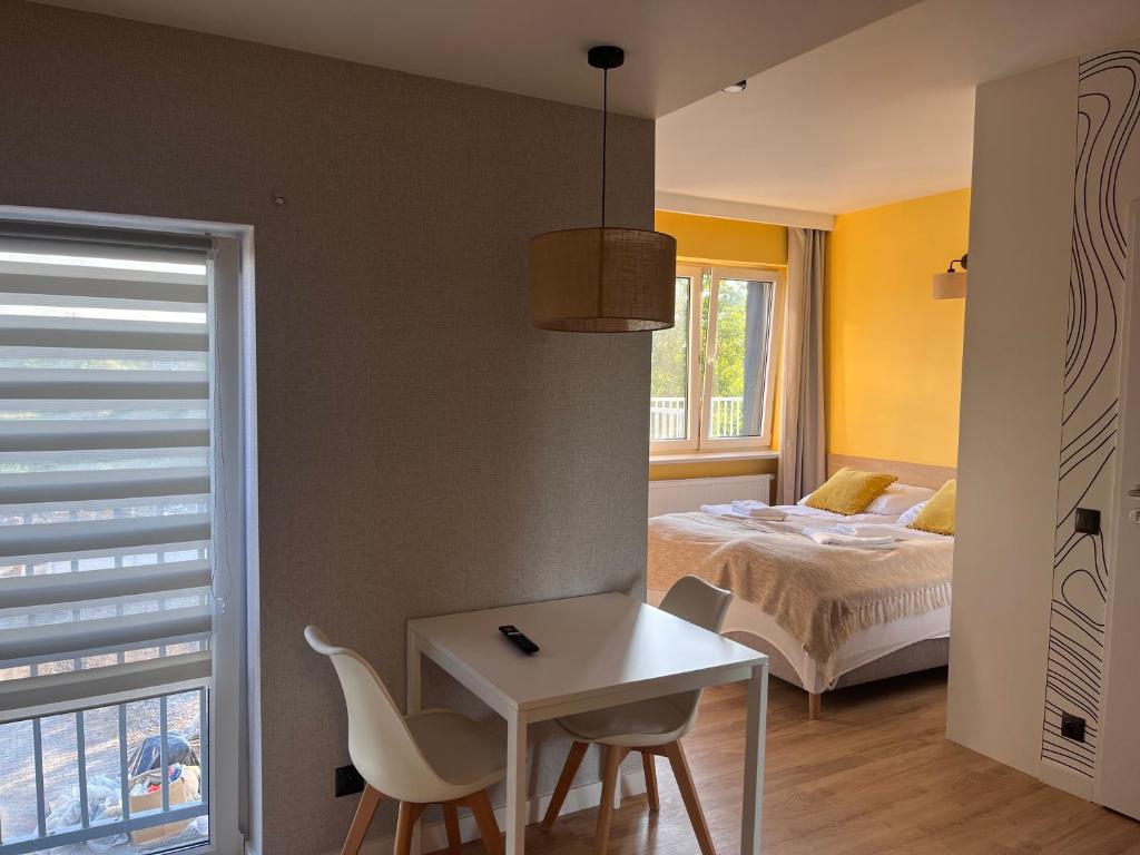 Small white dining table and chairs in compact suite, view into bright yellow bedroom.