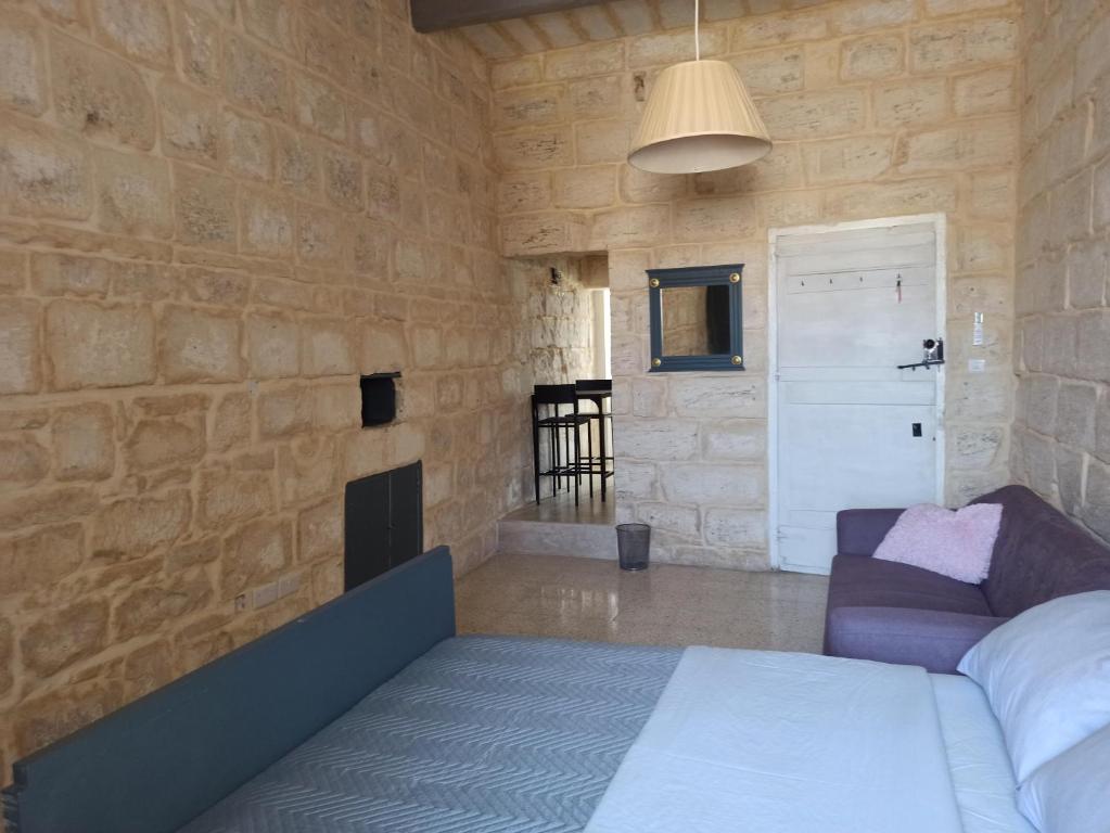 a bedroom with a stone wall with a bed and a couch at Beautiful 1-Bed Apartment in Hal Qormi in Qormi