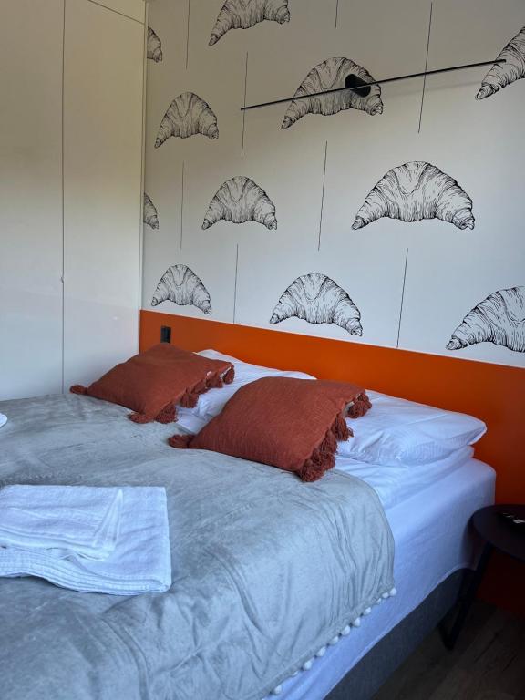 Twin beds pushed together with orange headboard, croissant-patterned wallpaper and rust-colored pillows.