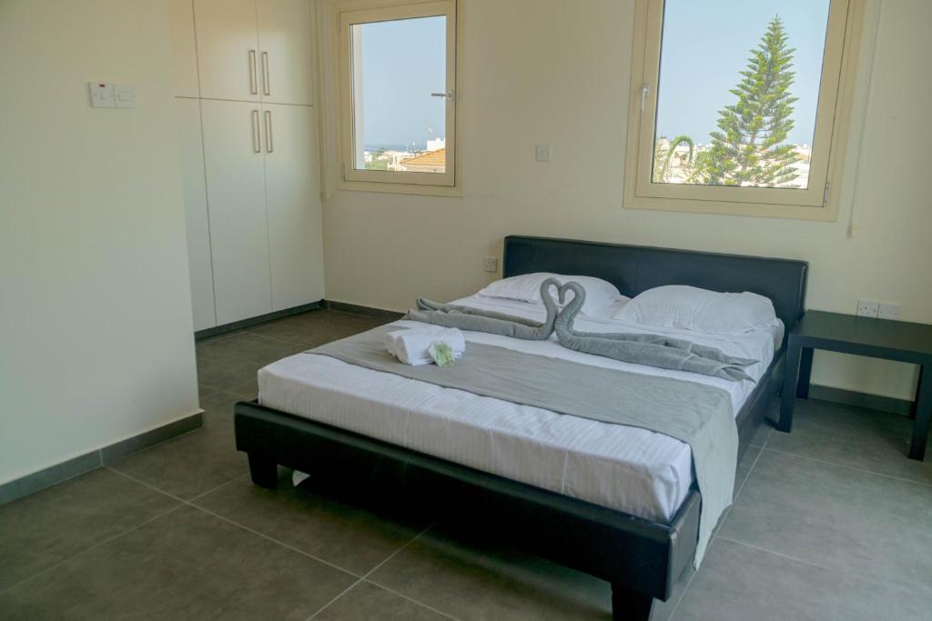 1 cama grande en un dormitorio con 2 ventanas en Lydia's Villa, en Protaras
