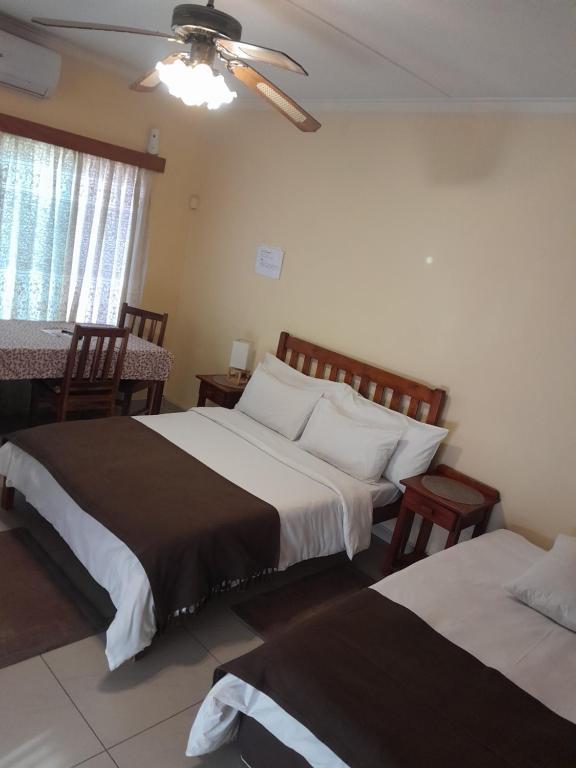 a bedroom with two beds and a table and window at Eve's Accommodation in Windhoek