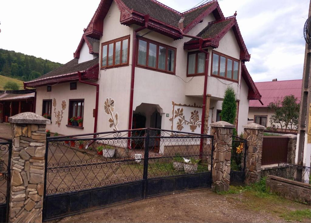 una casa blanca con una puerta y una valla en Casa Simerea, en Mălini