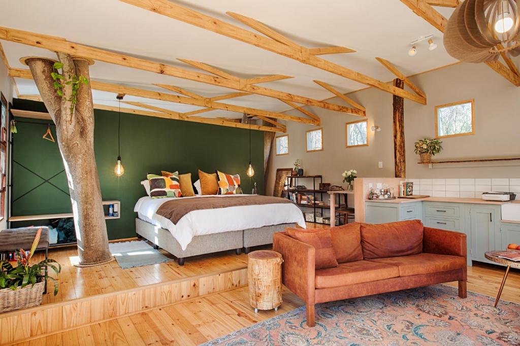ein Schlafzimmer mit einem Bett und einem Sofa in einem Zimmer in der Unterkunft Elsewhere Treehouse and Apartment on the River in Muldersdrift