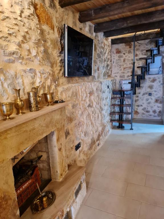 a stone walled room with a stone fireplace and stairs at Village home in Chios