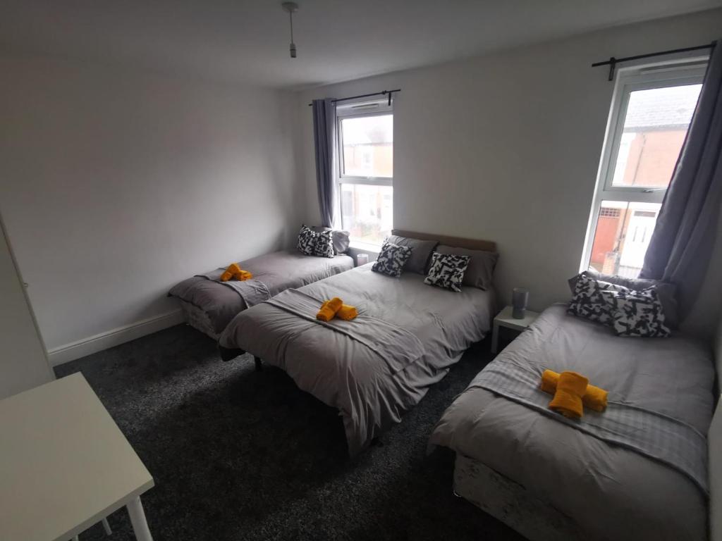 Cette chambre comprend 3 lits avec des archets orange. dans l'établissement Family Room - Sutherland Place, à Derby