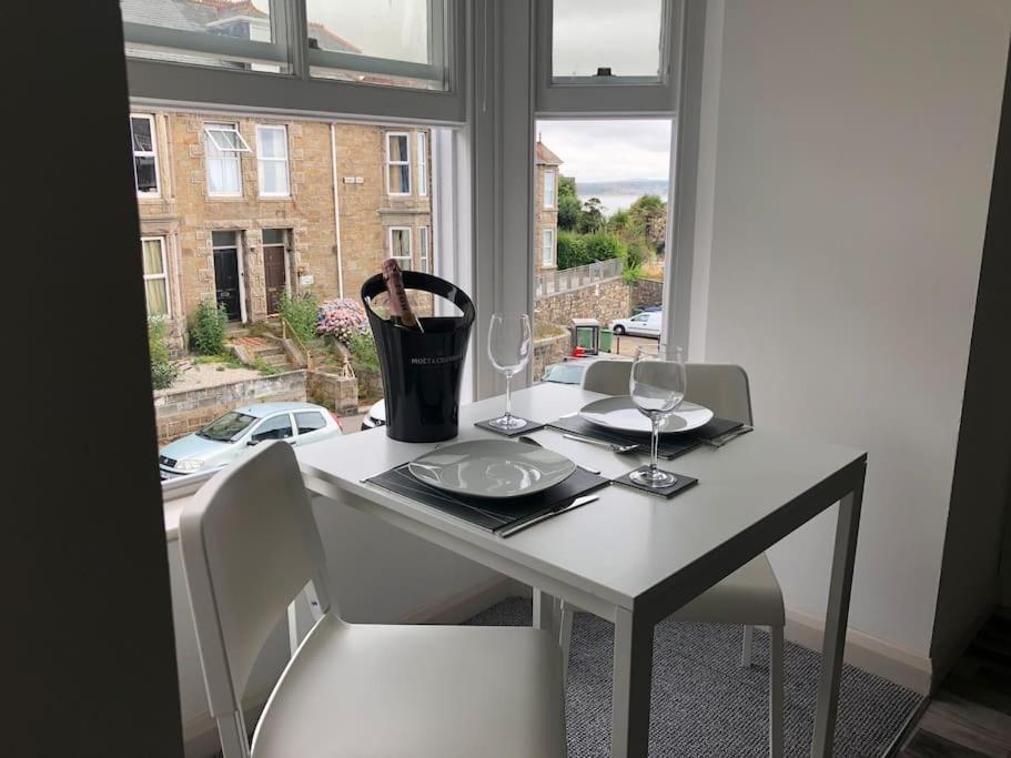 a white table with two chairs and a window at Newly Renovated Modern Studio Apartment in Penzance