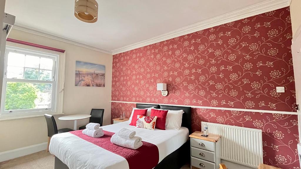 a bedroom with two beds and a red wall at Tusker Lodge in Torquay