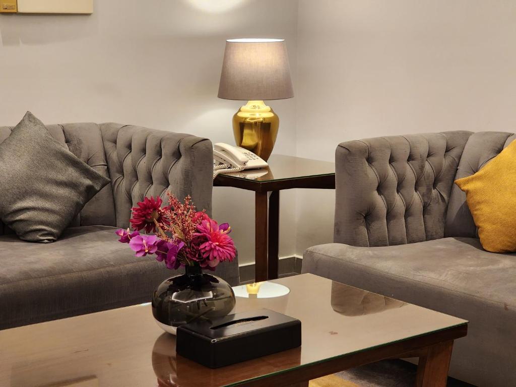 un soggiorno con due divani e un tavolo con fiori di دار ود للأجنحة الفندقية Dar Wed a Gedda