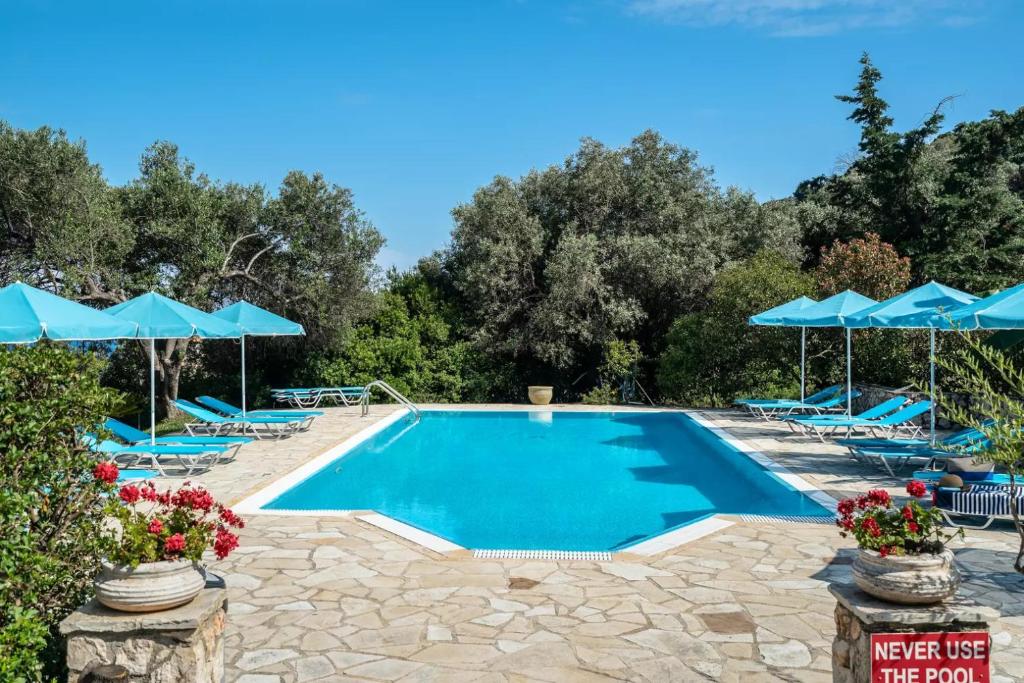 a swimming pool with blue umbrellas and chairs at Anemona studio 1 in Katelios