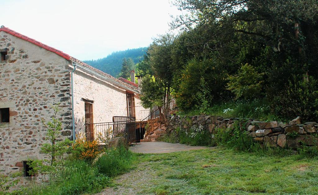 a stone building and a stone wall next to a house at Auberge de Lascours in Ceilhes-et-Rocozels