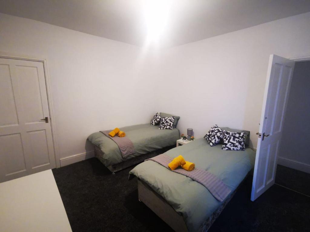 een slaapkamer met twee bedden met gele kussens erop bij Twin Room - Sutherland Place in Derby