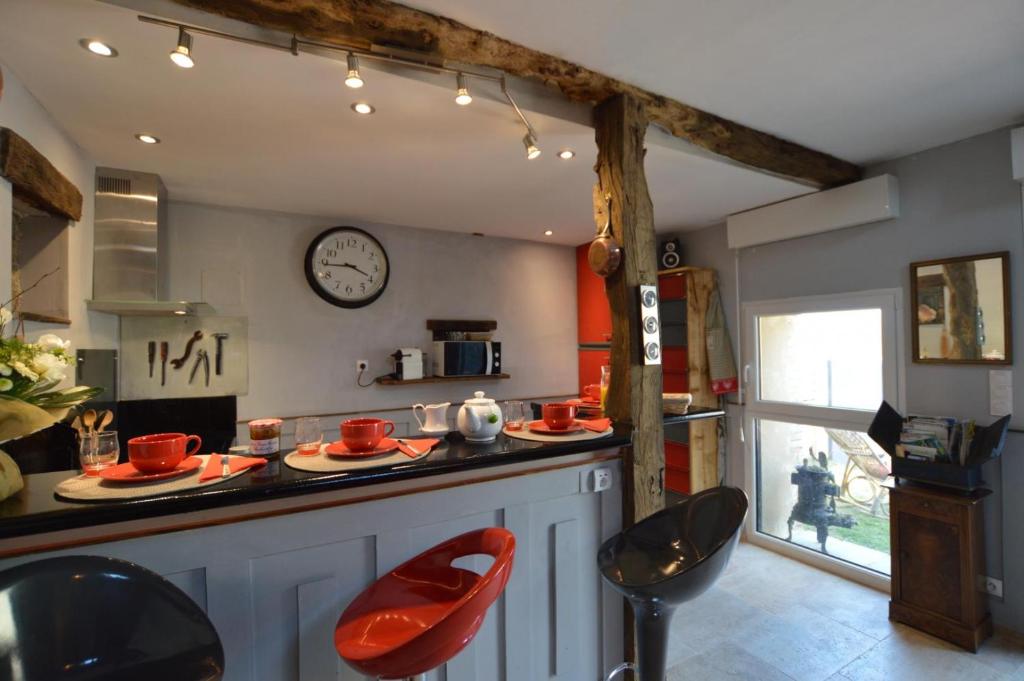 a kitchen with a counter with red chairs and a clock at La porcherie du pet en l&#39;air in Saint Malo