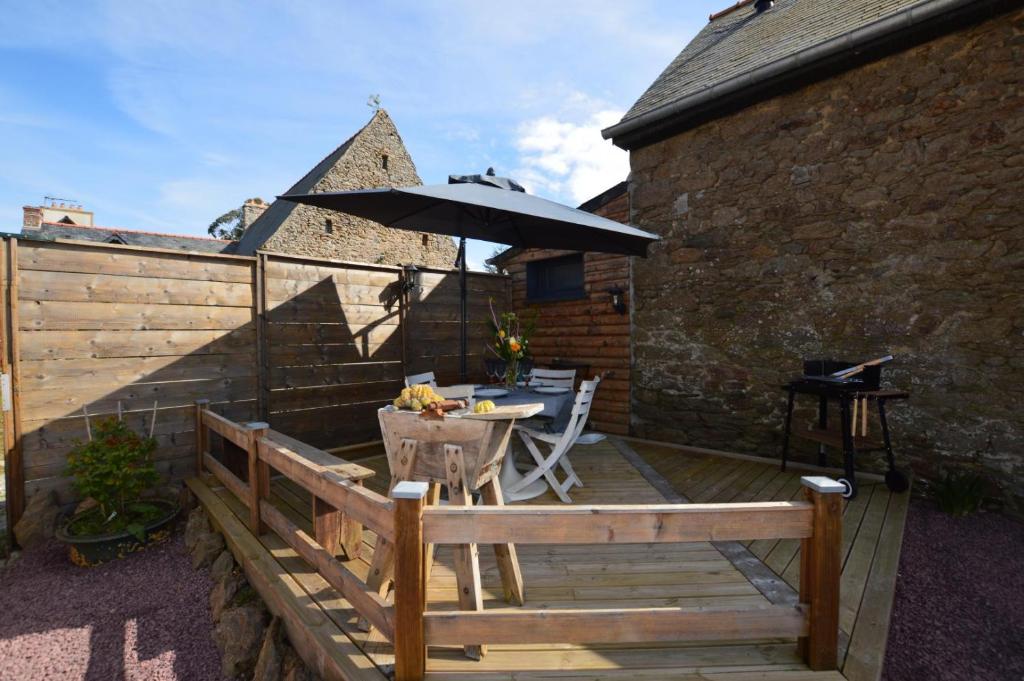 a wooden deck with a table and an umbrella at La porcherie du pet en l&#39;air in Saint Malo