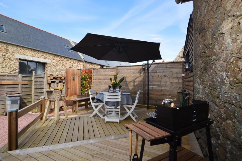 a wooden deck with a table and an umbrella at La porcherie du pet en l&#39;air in Saint Malo