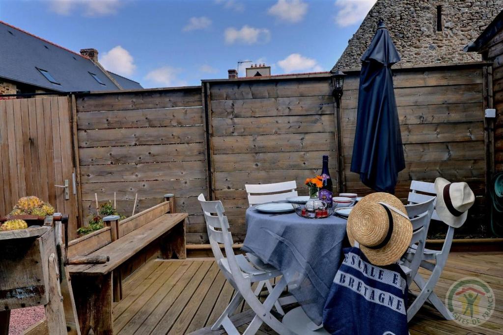 a table and chairs on a deck with a umbrella at La porcherie du pet en l&#39;air in Saint Malo