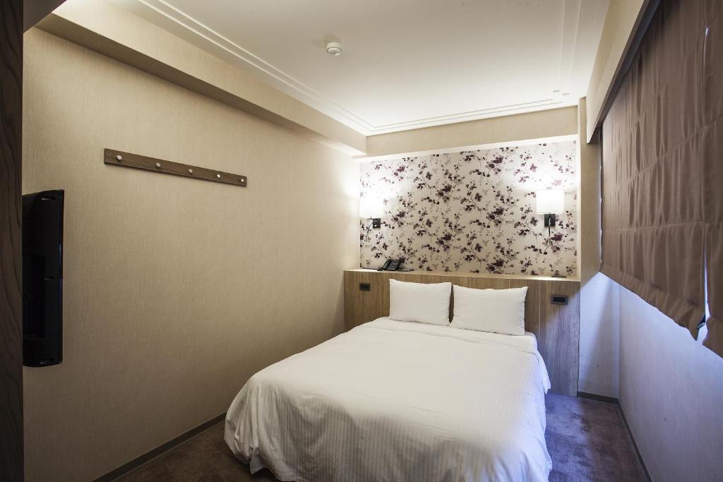 a bedroom with a white bed and a tv at Citizen Hotel in Taipei