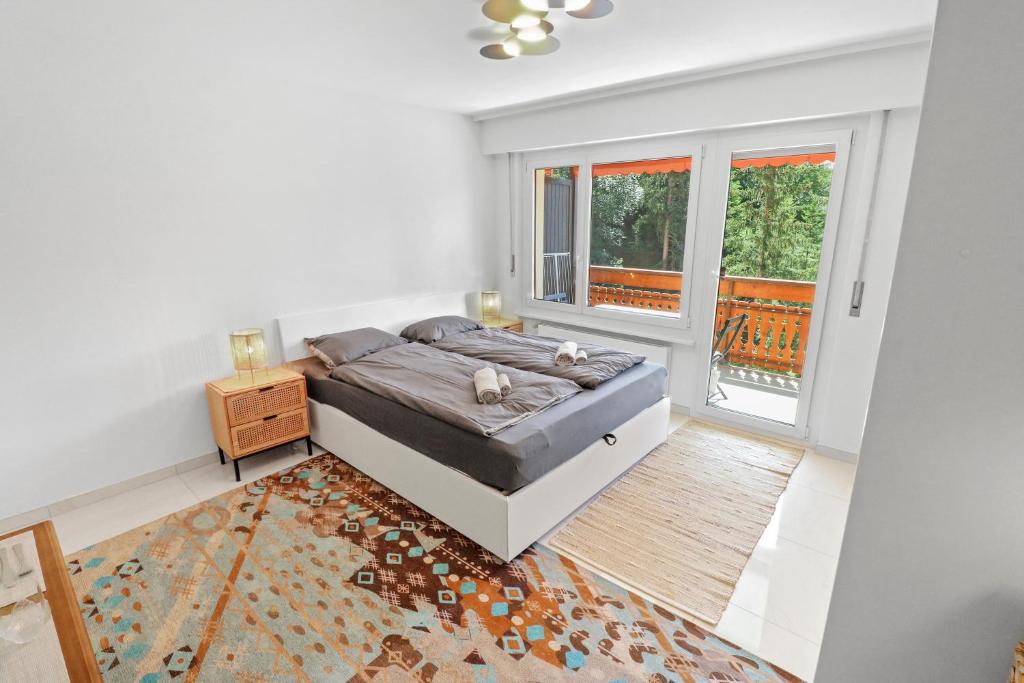 een witte slaapkamer met een bed en een raam bij Studio paisible et chaleureux in Crans-Montana