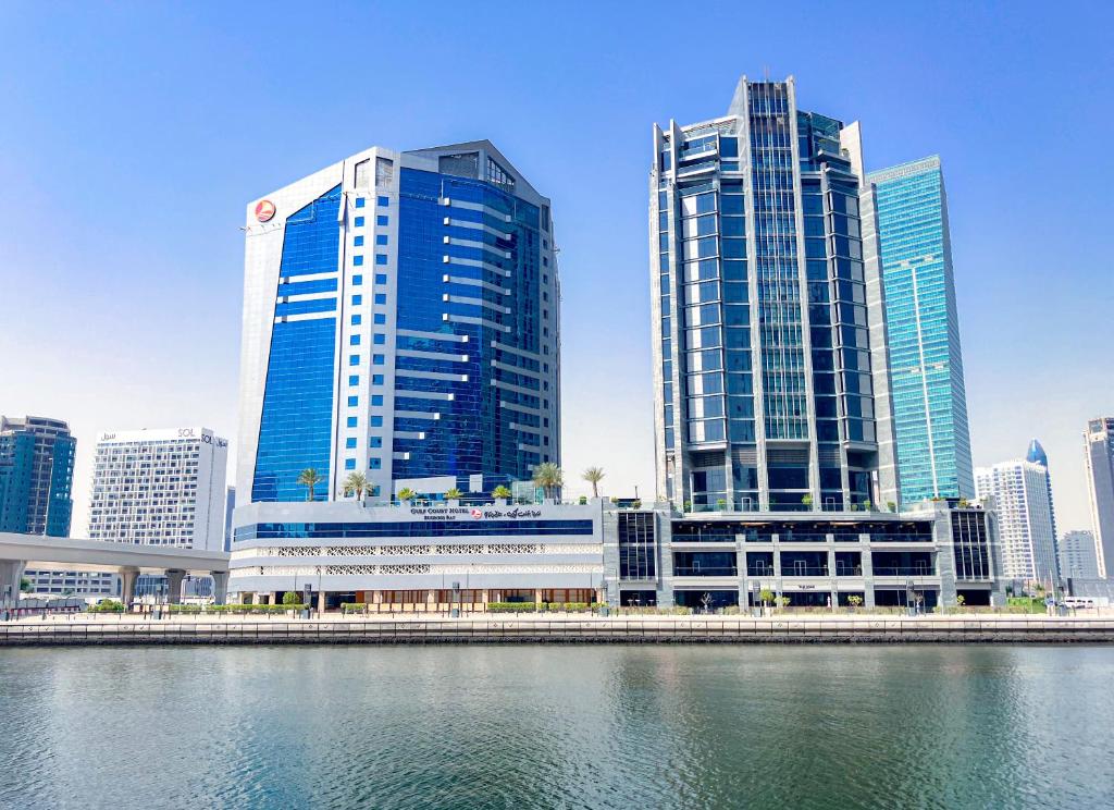 Gulf Court Hotel Business Bay في دبي: مدينة ذات مباني طويلة وجسم ماء