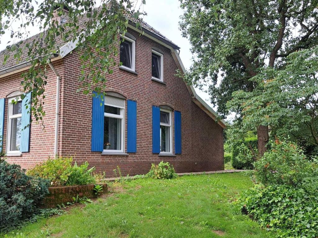 een oud bakstenen huis met blauwe ramen en een tuin bij Pleasant Holiday Home in Haps with garden in Haps