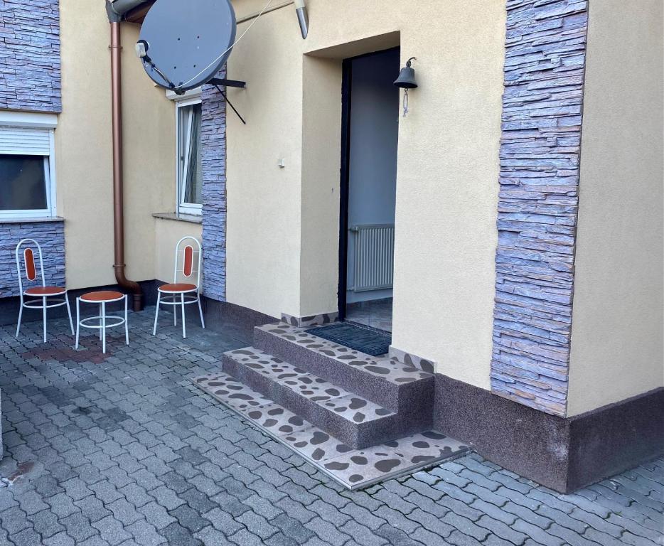 - un bâtiment avec deux chaises et une porte dans l'établissement House Damado Deluxe, à Öttevény