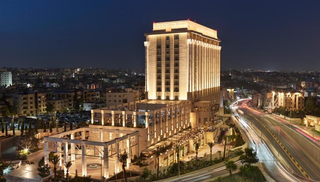 a large building with a lit up tower at night at Four Seasons Hotel Amman in Amman