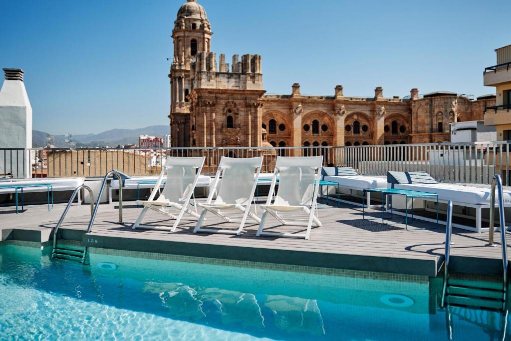 um grupo de cadeiras sentadas num deque ao lado de uma piscina em Molina Lario em Málaga