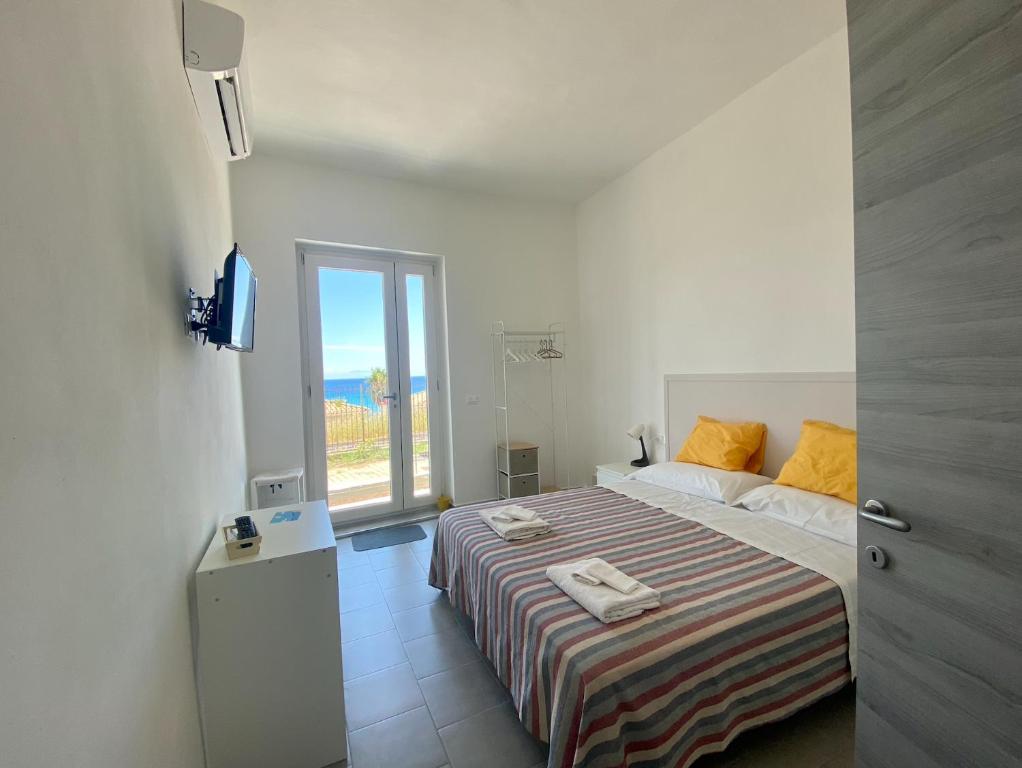 una camera bianca con un letto e una finestra di Amoenus Bed & Breakfast a Soverato Marina