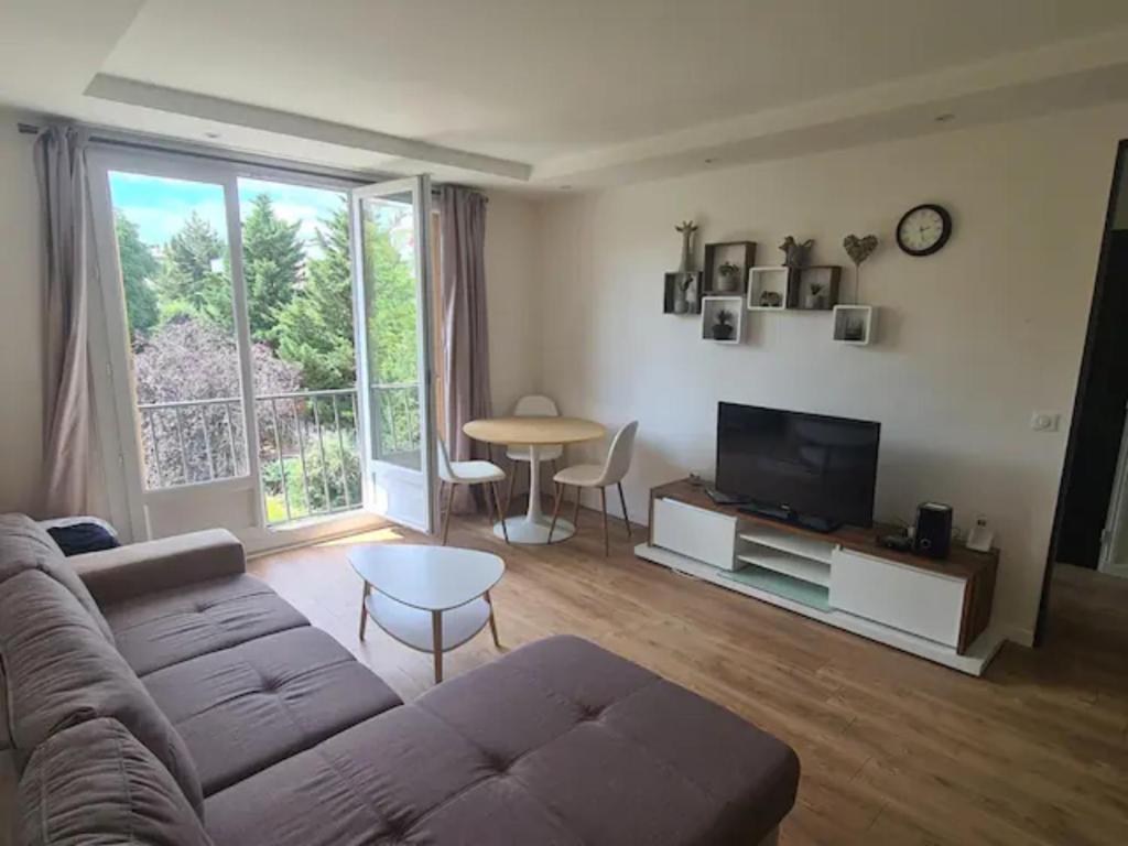 sala de estar con sofá, TV y mesa en Sunny and renovated flat in secure residence, en La Garenne-Colombes
