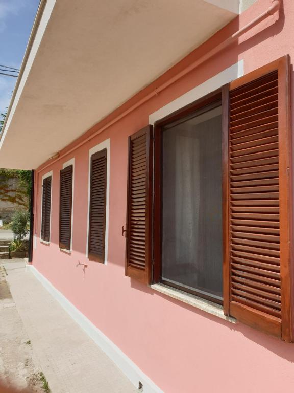a pink building with wooden shutters on it at Casa vacanza in Zungri