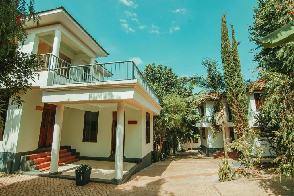 ein weißes Haus mit einem Balkon und Bäumen in der Unterkunft Bamboo Village in Arusha