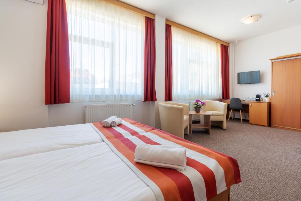 Fordan Hotel Pécs في بيتْش: غرفة فندق بسرير كبير مع ستائر حمراء