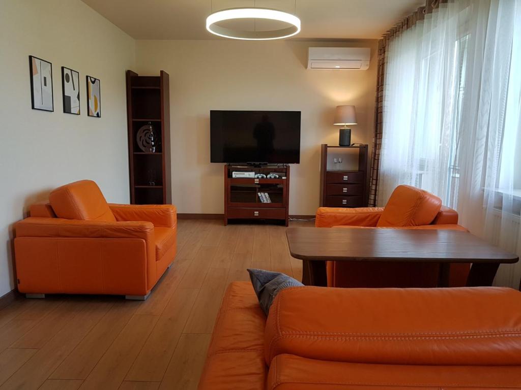 a living room with orange furniture and a flat screen tv at Wigilijna Apartament in Lublin