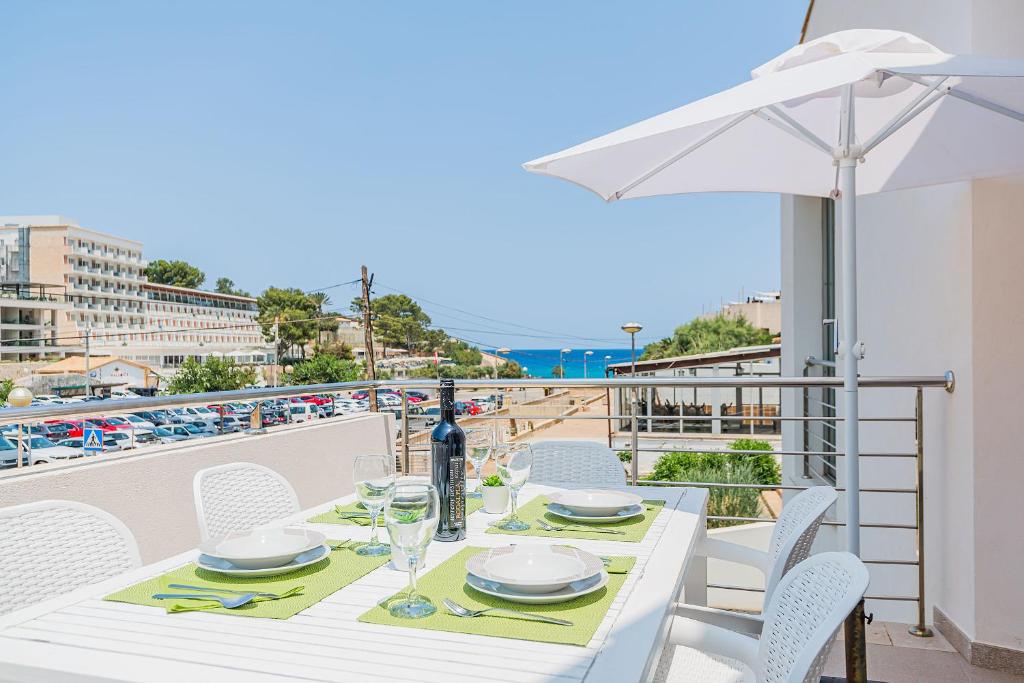 een witte tafel met stoelen en een parasol op een balkon bij Molins 6 in Cala de Sant Vicent