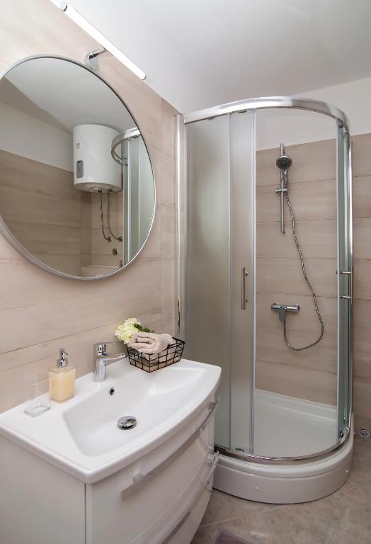 a bathroom with a shower and a sink and a mirror at Apartmani Krmek in Mlini