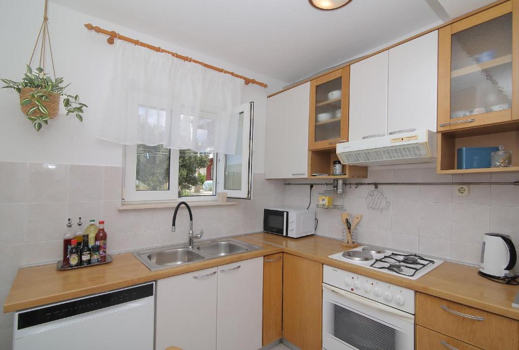 a kitchen with white cabinets and a sink at Apartmani Krmek in Mlini