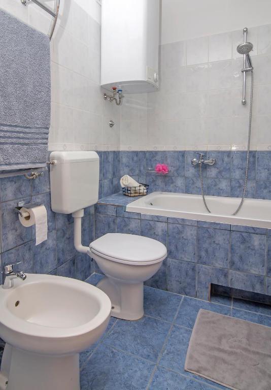 a bathroom with a toilet and a sink and a tub at Apartmani Krmek in Mlini