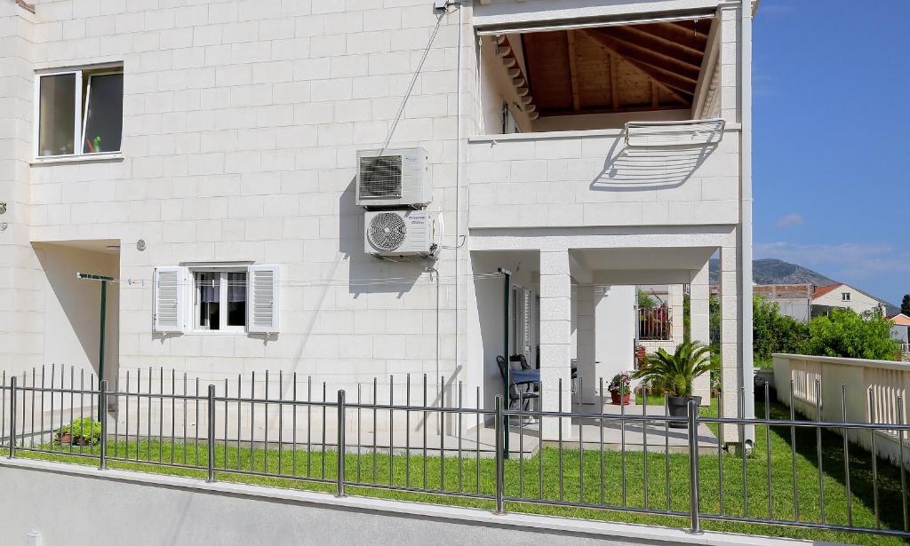 a white house with a fence in front of it at Apartmani Krmek in Mlini
