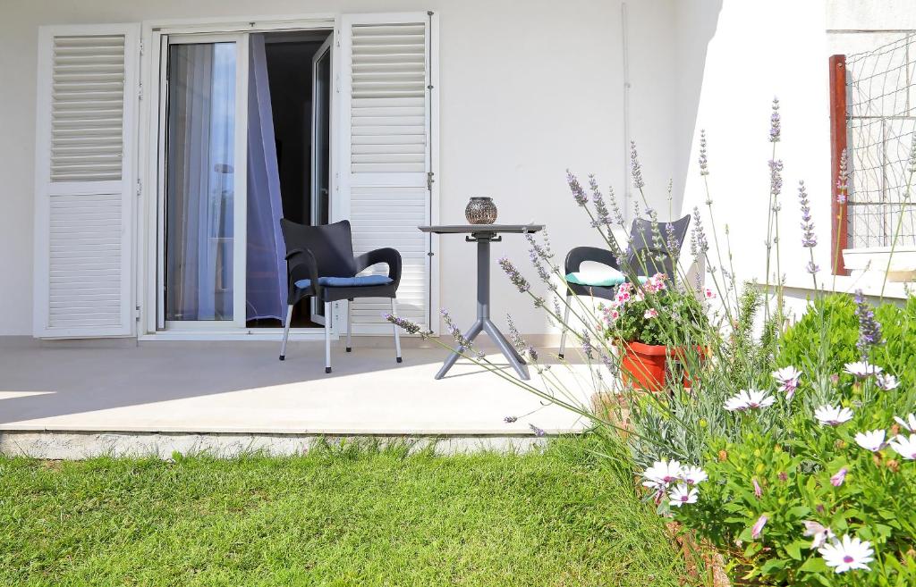 a patio with a table and chairs and flowers at Apartmani Krmek in Mlini