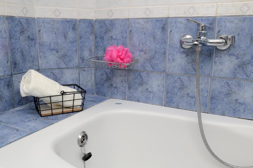 a bathroom with a bath tub with a pink flower in a basket at Apartmani Krmek in Mlini