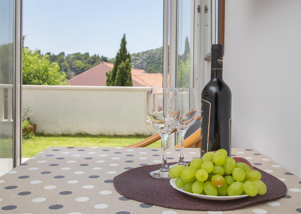 a table with wine glasses and a plate of grapes at Apartmani Krmek in Mlini