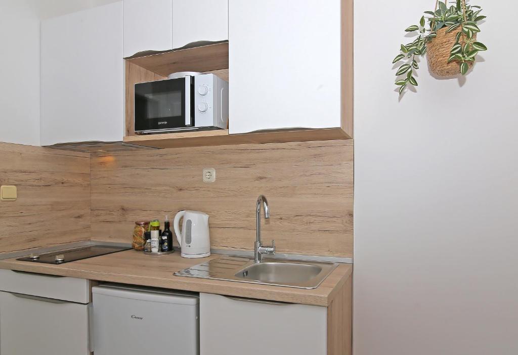 a kitchen with a sink and a microwave at Apartmani Krmek in Mlini