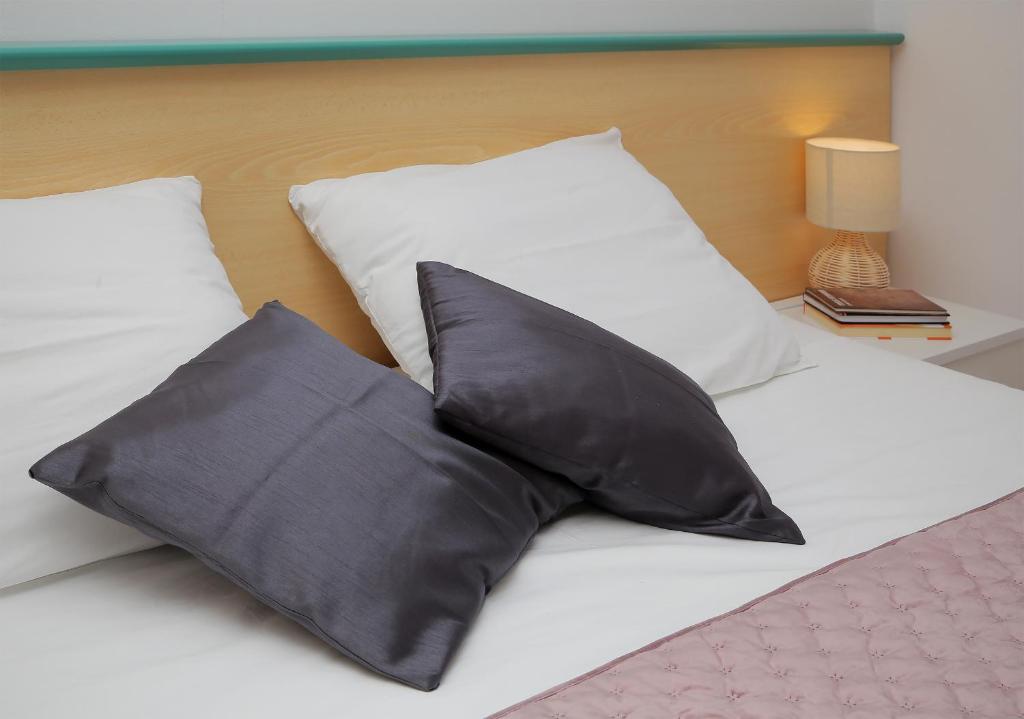 a bed with two black pillows on it at Apartmani Krmek in Mlini