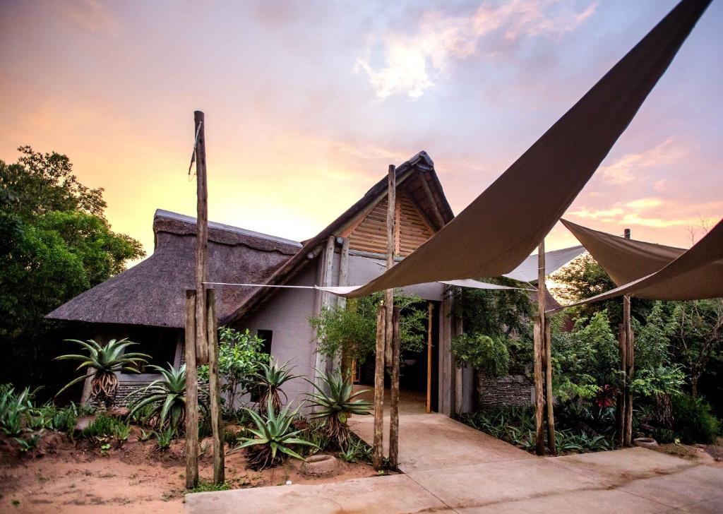 una casa con techo de paja y postes de madera en Royal Thonga Safari Lodge en Sihangwane