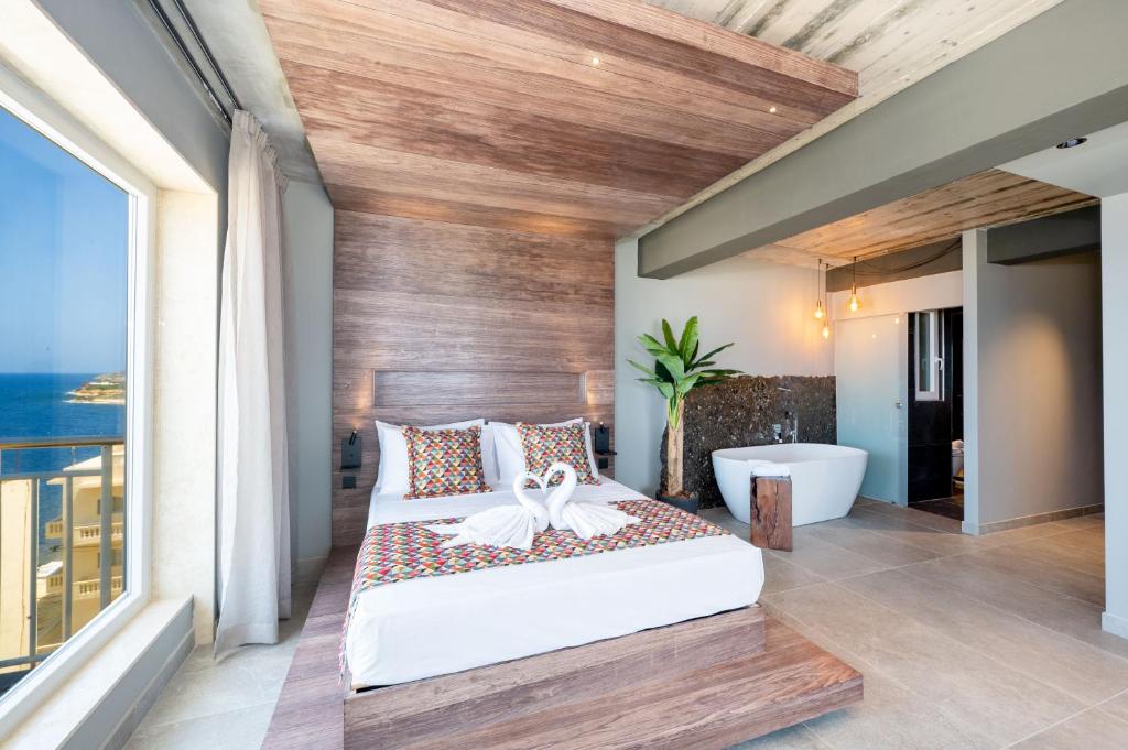 a bedroom with a large bed and a bath tub at Salini Suites in Żebbuġ