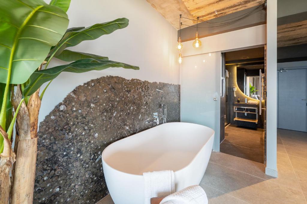 a bathroom with a white bath tub next to a wall at Salini Suites in Żebbuġ