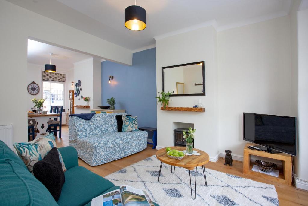 a living room with a blue couch and a tv at Budleigh Burrow in Budleigh Salterton