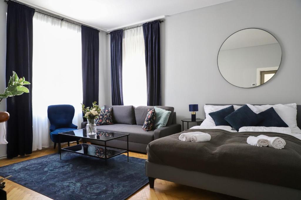 ein Schlafzimmer mit einem Bett, einem Sofa und einem Spiegel in der Unterkunft Modern Apartment, 3 min to "U3 Neubaugasse" in Wien
